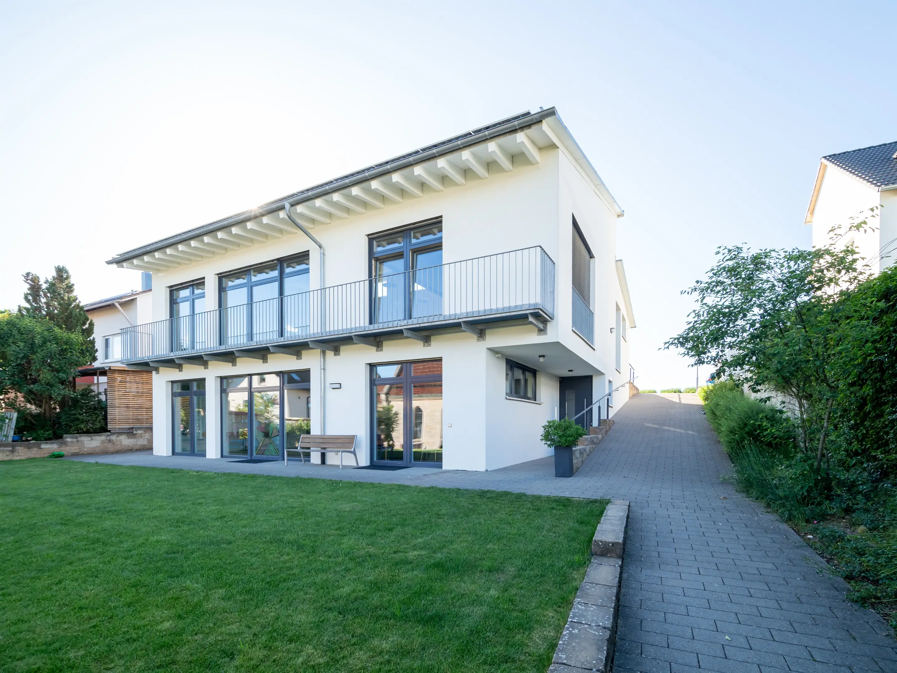 Gartenseite eines Gemeindehauses mit Balkon und Terrasse