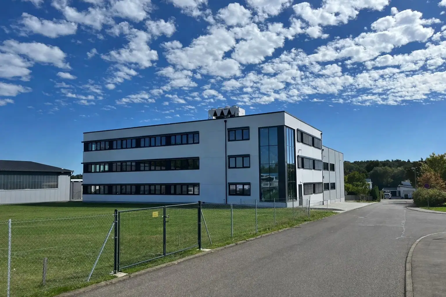 Gewerbegebäude mit Büroriegel in ganzer Länge und verglaster Treppenhausecke, Straßenansicht