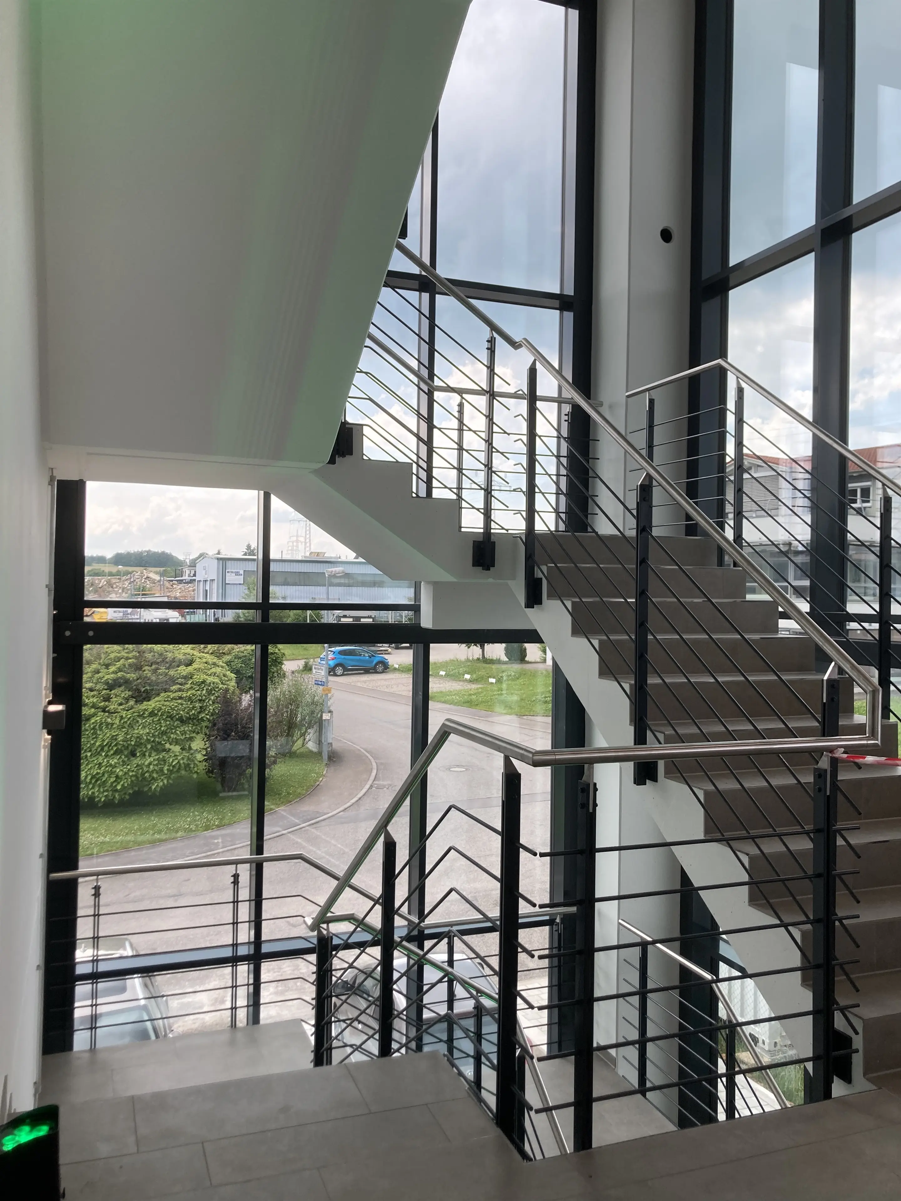 Treppenhaus mit Stahlgeländer vor raumhoher Verglasung
