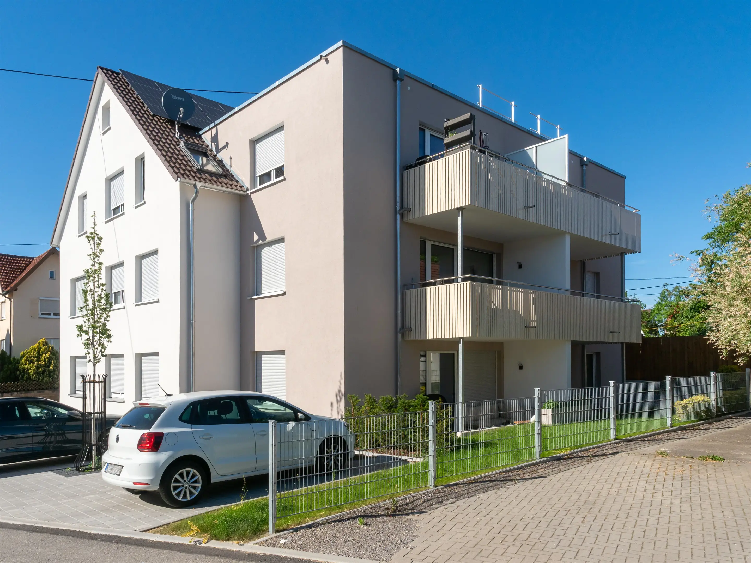 Gartenseite eines Mehrfamilienhauses mit Balkonen und Photovoltaikdach